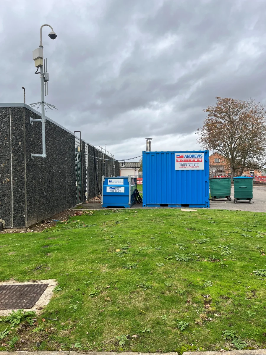 Engineer setting up boiler hoses and fittings for emergency heating at university bioscience lab