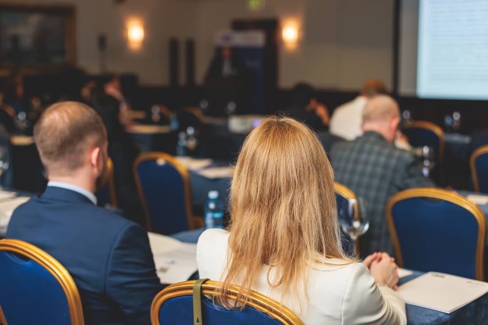 Guests attending a conference in hotel event space cooled using temporary air conditioning hire